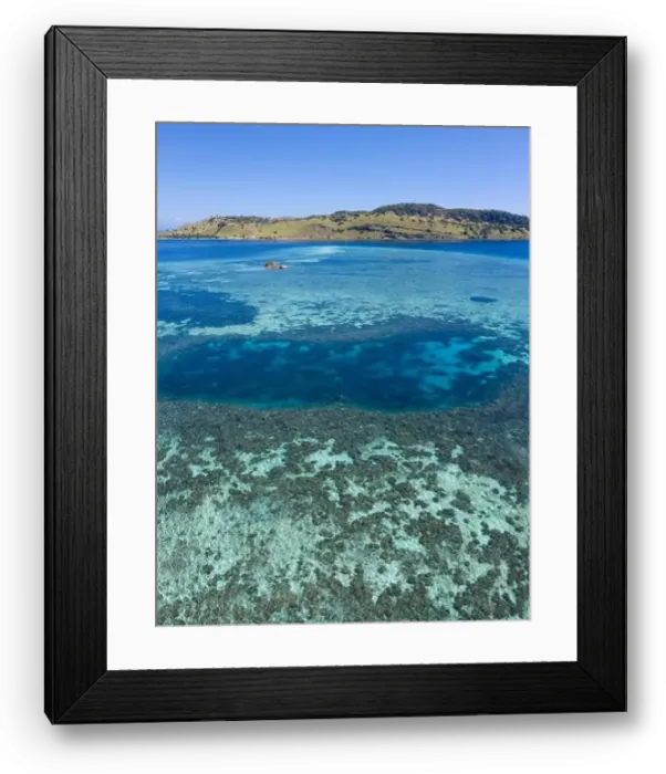 Framed Print : Seen from a bird's eye view, an idyllic tropical island is surrounded by a healthy coral reef in Komodo National Park