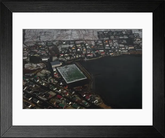 Framed Print : Aerial shot of the Faroese village Sandavagur as seen from a helicopter flight over snow-covered landscape in early Framed Print : Aerial shot of the Faroese village Sandavagur as seen from a helicopter flight over snow-covered landscape in early