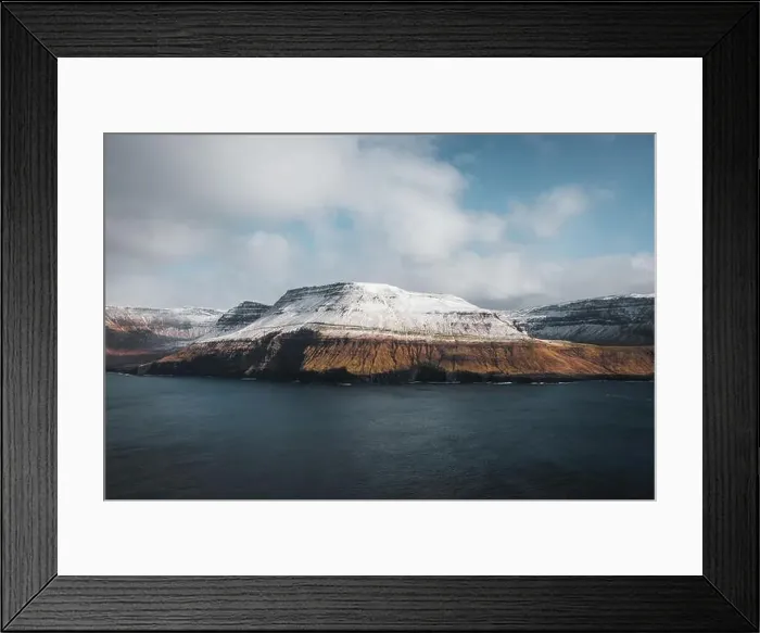 Framed Print : Aerial helicopter shot of snow-covered mountains at the shore of the Faroe Islands with low-hanging clouds during cold Framed Print : Aerial helicopter shot of snow-covered mountains at the shore of the Faroe Islands with low-hanging clouds during cold