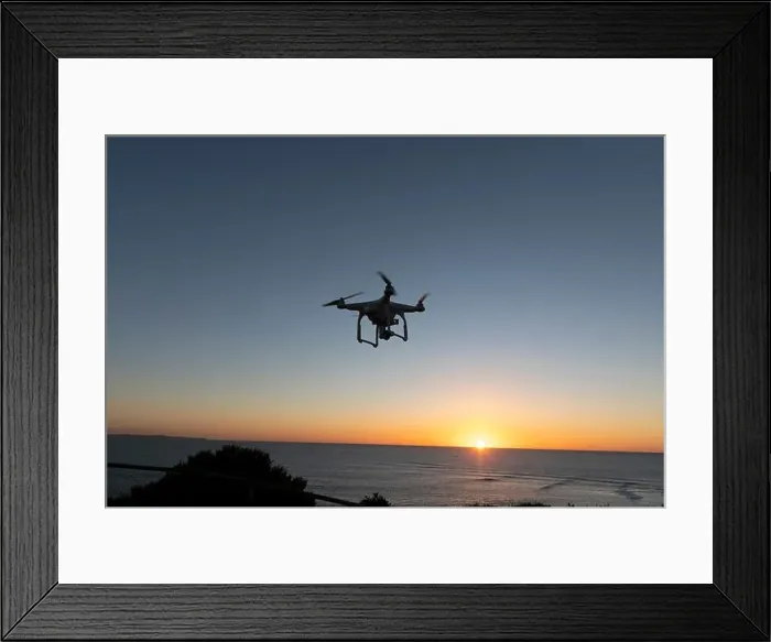 Framed Print : Professional Drone flying at Sunrise over the sea. The sky is glowing Framed Print : Professional Drone flying at Sunrise over the sea. The sky is glowing