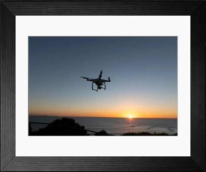 Framed Print : Professional Drone flying at Sunrise over the sea. The sky is glowing Framed Print : Professional Drone flying at Sunrise over the sea. The sky is glowing