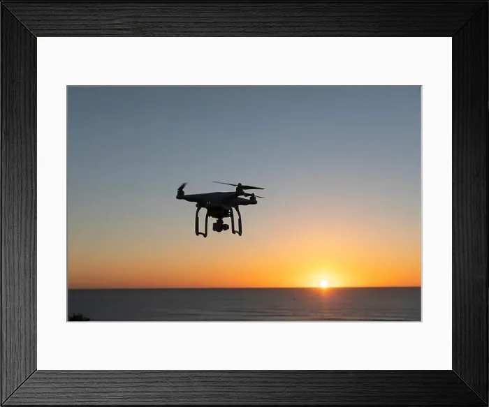 Framed Print : Professional Drone flying at Sunrise over the sea. The sky is glowing Framed Print : Professional Drone flying at Sunrise over the sea. The sky is glowing