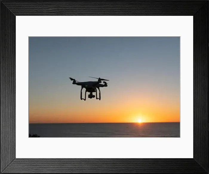 Framed Print : Professional Drone flying at Sunrise over the sea. The sky is glowing Framed Print : Professional Drone flying at Sunrise over the sea. The sky is glowing