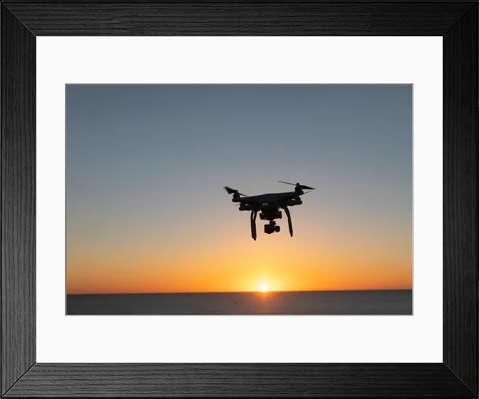Framed Print : Professional Drone flying at Sunrise over the sea. The sky is glowing Framed Print : Professional Drone flying at Sunrise over the sea. The sky is glowing