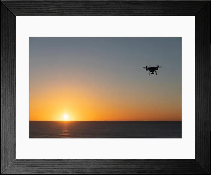 Framed Print : Professional Drone flying at Sunrise over the sea. The sky is glowing Framed Print : Professional Drone flying at Sunrise over the sea. The sky is glowing
