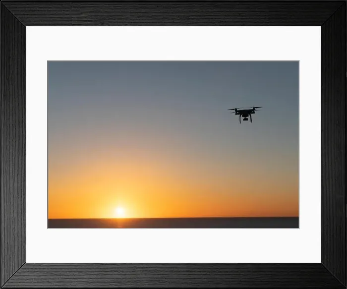 Framed Print : Professional Drone flying at Sunrise over the sea. The sky is glowing Framed Print : Professional Drone flying at Sunrise over the sea. The sky is glowing