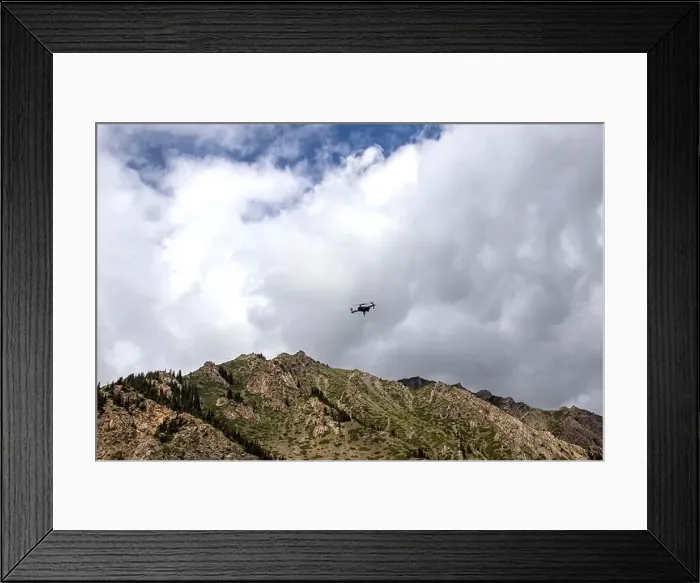 Framed Print : Drone in the cloudy sky over a mountain range. Traveling in Kyrgyzstan. Naryn Region Framed Print : Drone in the cloudy sky over a mountain range. Traveling in Kyrgyzstan. Naryn Region