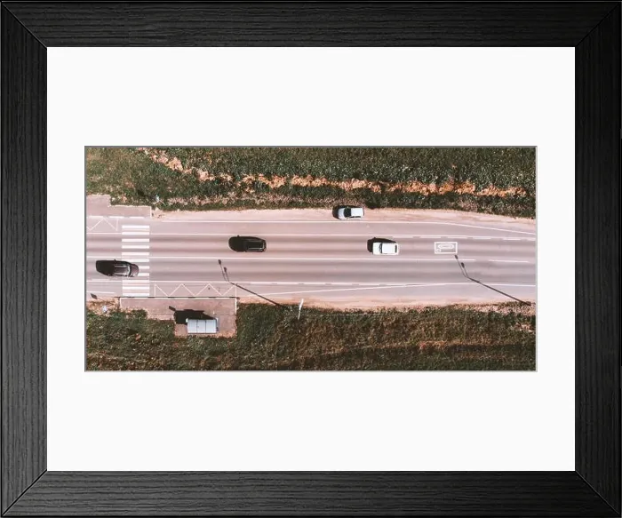 Framed Print : Drone view of moving cars on country side road with crosswalk, bus stop and field around Framed Print : Drone view of moving cars on country side road with crosswalk, bus stop and field around