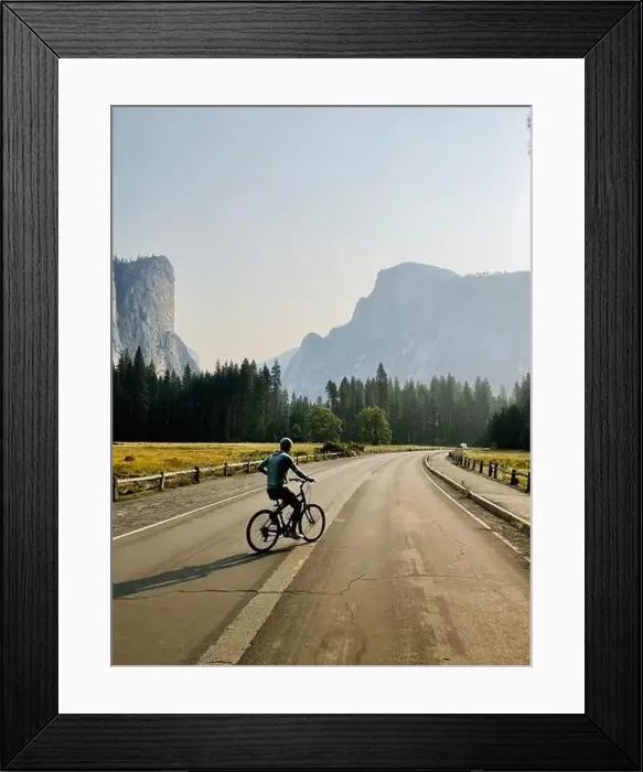 Framed Print : A male rides a bike in the lower Yosemite Valley with beautiful views of Half Dome