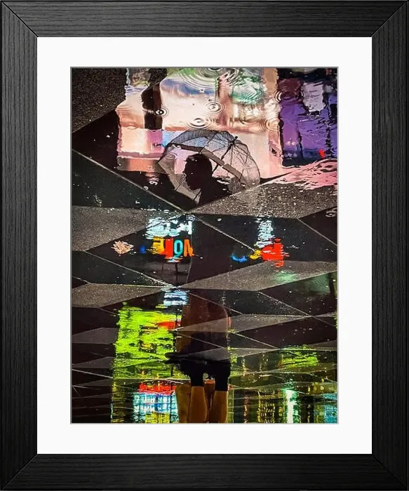 Framed Print : Reflection of a standing man holding an umbrella surrounded by colorful neon lights as seen in the reflection on wet Framed Print : Reflection of a standing man holding an umbrella surrounded by colorful neon lights as seen in the reflection on wet