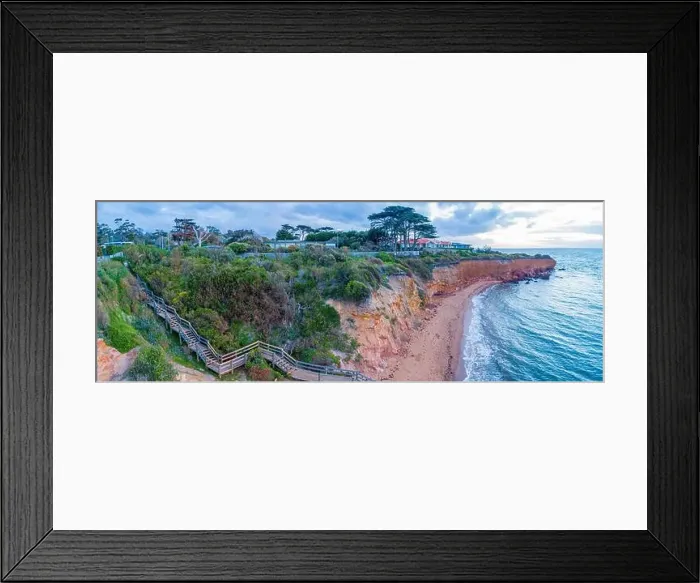 Framed Print : Wooden stairs descending to secluded ocean beach below cliff at sunset Framed Print : Wooden stairs descending to secluded ocean beach below cliff at sunset