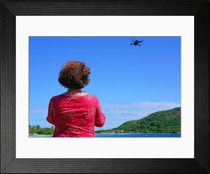 Framed Print : ST KITTS, ST KITTS AND NEVIS -21 NOV 2018- A woman taking pictures with a drone camera over the Caribbean Sea in Framed Print : ST KITTS, ST KITTS AND NEVIS -21 NOV 2018- A woman taking pictures with a drone camera over the Caribbean Sea in