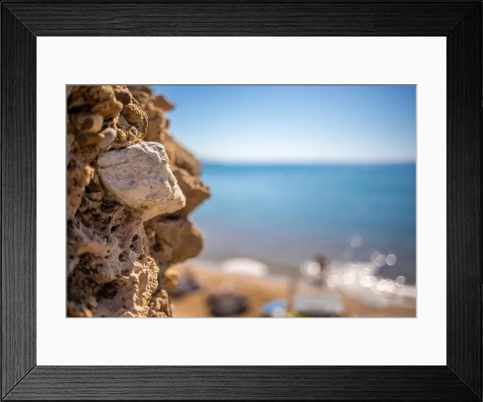 Framed Print : in the foreground is a stone wall and in the background is the blue sea in beautiful weather Framed Print : in the foreground is a stone wall and in the background is the blue sea in beautiful weather