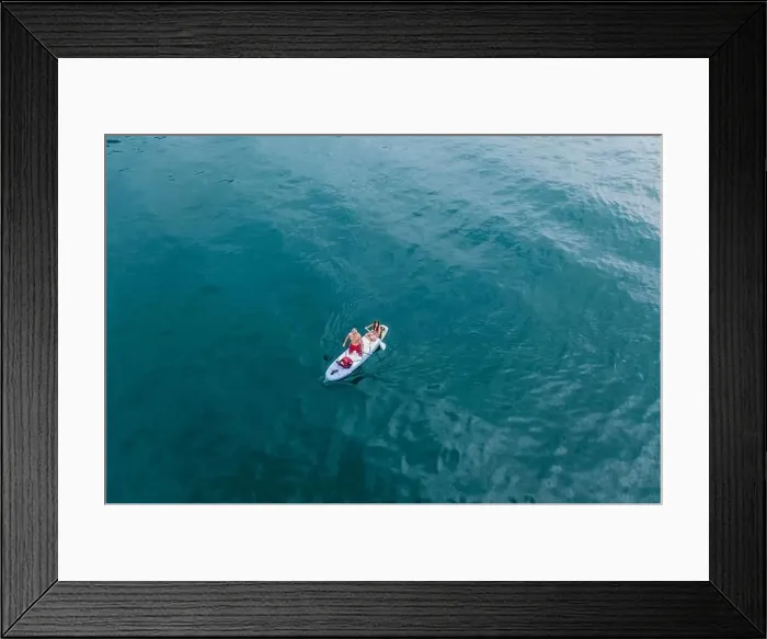 Framed Print : Malcesine, Italy - August 7, 2019: Aerial drone shot view of a man and young girl on surfboard in lake garda Framed Print : Malcesine, Italy - August 7, 2019: Aerial drone shot view of a man and young girl on surfboard in lake garda