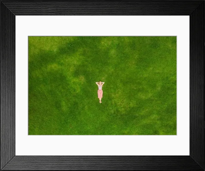 Framed Print : Young woman lying down in the middle of a field and relaxing, drone photo Framed Print : Young woman lying down in the middle of a field and relaxing, drone photo