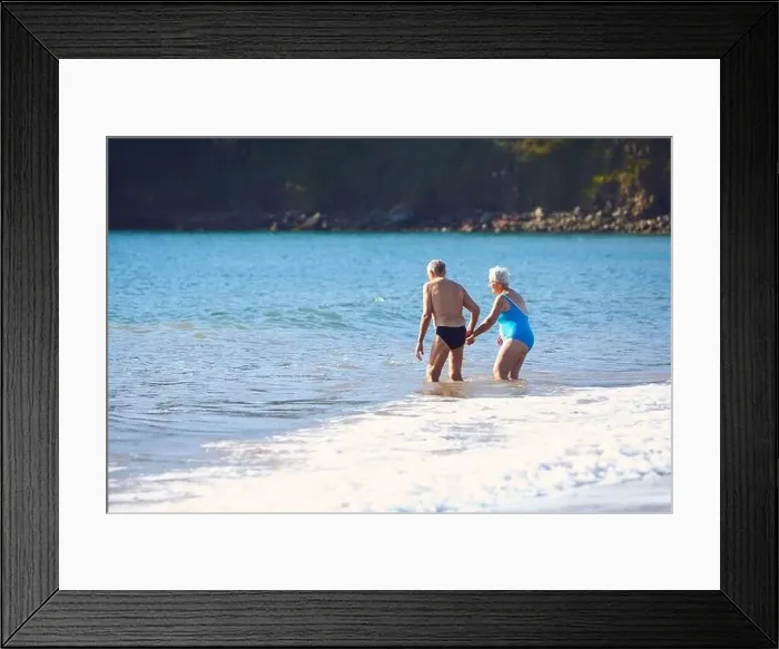 Framed Print : Loving Senior Couple Holding Hands As They Walk Into Sea For Swim Framed Print : Loving Senior Couple Holding Hands As They Walk Into Sea For Swim