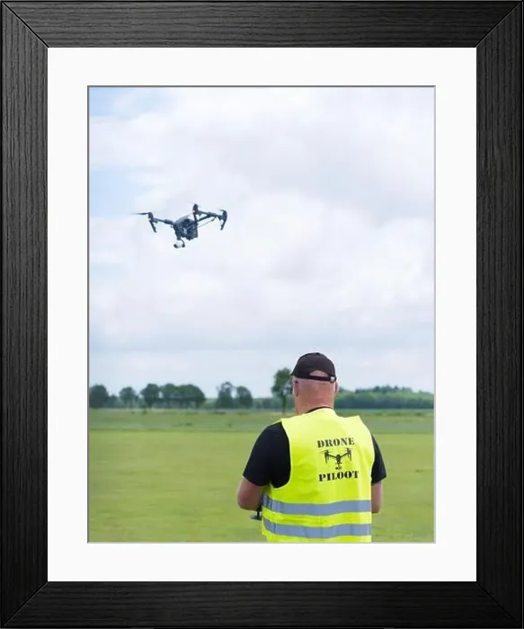 Framed Print : NIJVERDAL, NETHERLANDS - JUNE 23, 2018: Professional drone pilot controling a drone with camera Framed Print : NIJVERDAL, NETHERLANDS - JUNE 23, 2018: Professional drone pilot controling a drone with camera