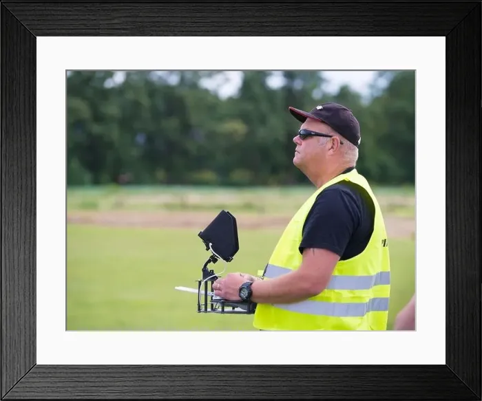 Framed Print : NIJVERDAL, NETHERLANDS - JUNE 23, 2018: Professional drone pilot controling a drone with camera Framed Print : NIJVERDAL, NETHERLANDS - JUNE 23, 2018: Professional drone pilot controling a drone with camera