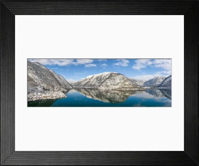Framed Print : Aerial panoramic drone shot of snow mountains by Halstatt lake and village in snow under blue cear sky during winter Framed Print : Aerial panoramic drone shot of snow mountains by Halstatt lake and village in snow under blue cear sky during winter