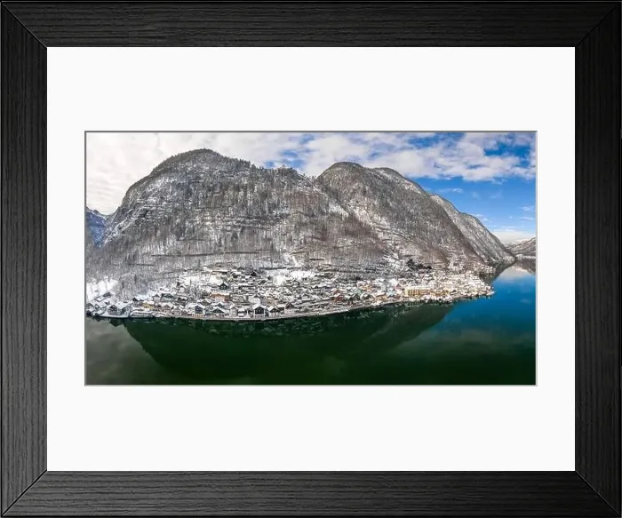 Framed Print : Aerial drone shot of Halstatt village at foot of snowy mountain under blue sky in winter time in austria Framed Print : Aerial drone shot of Halstatt village at foot of snowy mountain under blue sky in winter time in austria