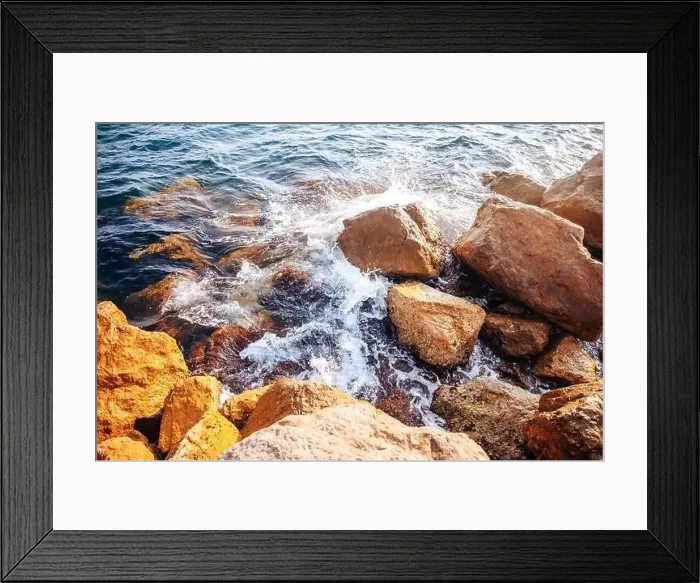 Framed Print : Stormy sea with waves and splashes breaks on sharp stones, warm day, light of sun Framed Print : Stormy sea with waves and splashes breaks on sharp stones, warm day, light of sun