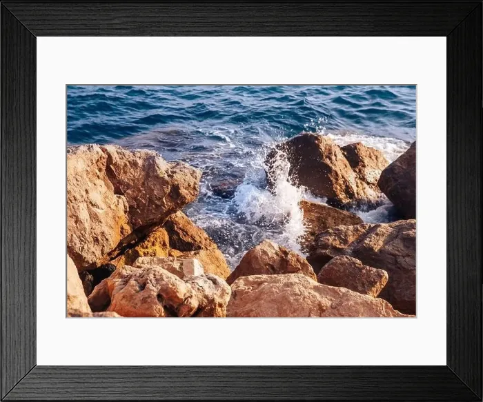 Framed Print : Stormy sea with waves and splashes breaks on sharp stones, warm day, light of sun Framed Print : Stormy sea with waves and splashes breaks on sharp stones, warm day, light of sun