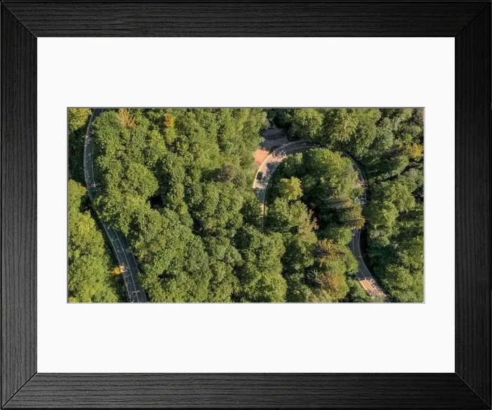 Framed Print : Curvy road through a green forest in spring, captured by a drone with a panoramic top view at springtime Framed Print : Curvy road through a green forest in spring, captured by a drone with a panoramic top view at springtime
