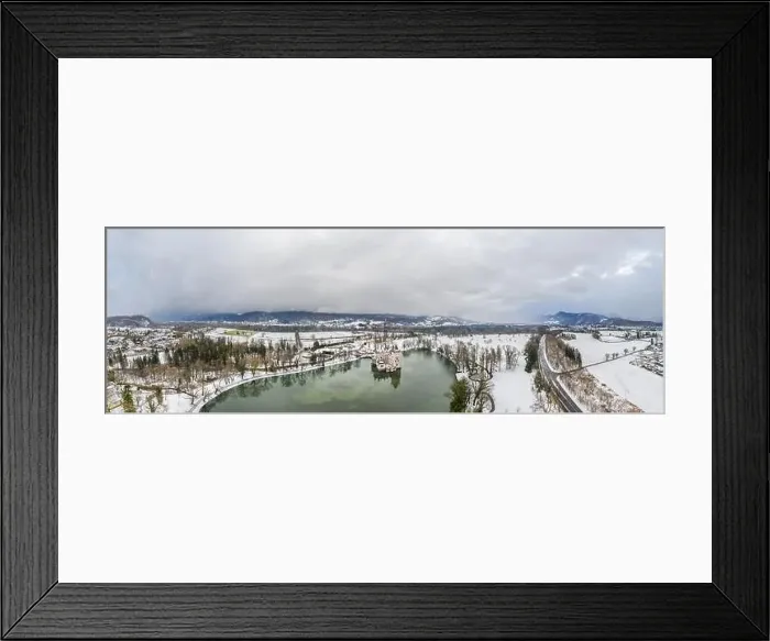 Framed Print : Panoramic aerial view of Schloss Anif moated castle in pond at Salzburg outskirts in heavy snow during winter with view