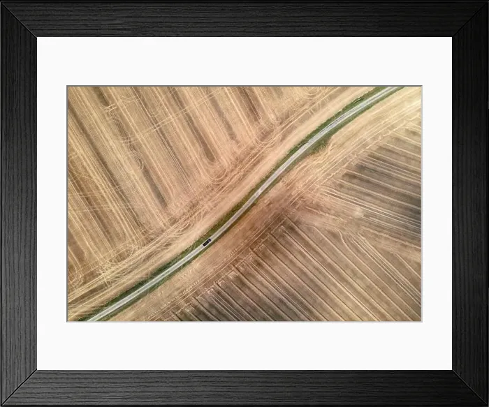 Framed Print : car driving on a rural little road surrounded by harvested fields, aerial drone view Framed Print : car driving on a rural little road surrounded by harvested fields, aerial drone view