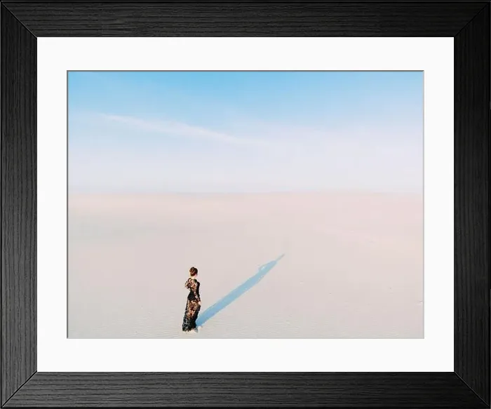Framed Print : Woman in lace black dress walks in desert and casts a shadow on white sand. View from drone Framed Print : Woman in lace black dress walks in desert and casts a shadow on white sand. View from drone