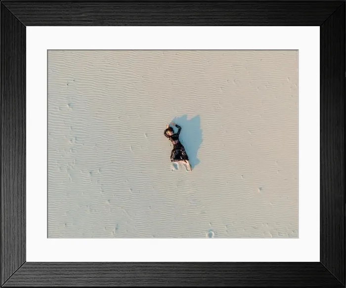 Framed Print : Woman in lace black dress lies in desert and casts a shadow on white sand. View from drone directly above Framed Print : Woman in lace black dress lies in desert and casts a shadow on white sand. View from drone directly above