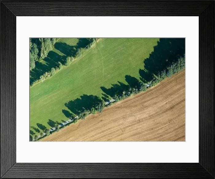 Framed Print : Aerial view of a green agricultural field with a rural road passing through it. Summer time, sunny day in landscape Framed Print : Aerial view of a green agricultural field with a rural road passing through it. Summer time, sunny day in landscape