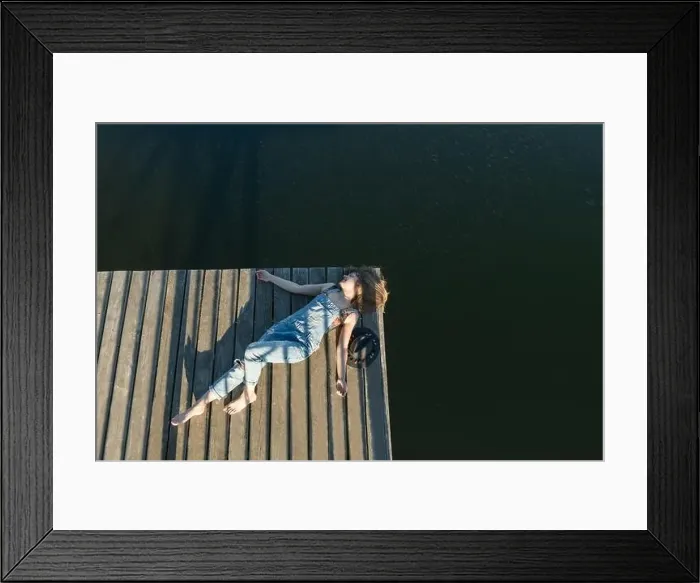 Framed Print : Top view of beautiful Woman in black swimsuit and hat lying down on wooden pier of lake on clear blue sky Framed Print : Top view of beautiful Woman in black swimsuit and hat lying down on wooden pier of lake on clear blue sky