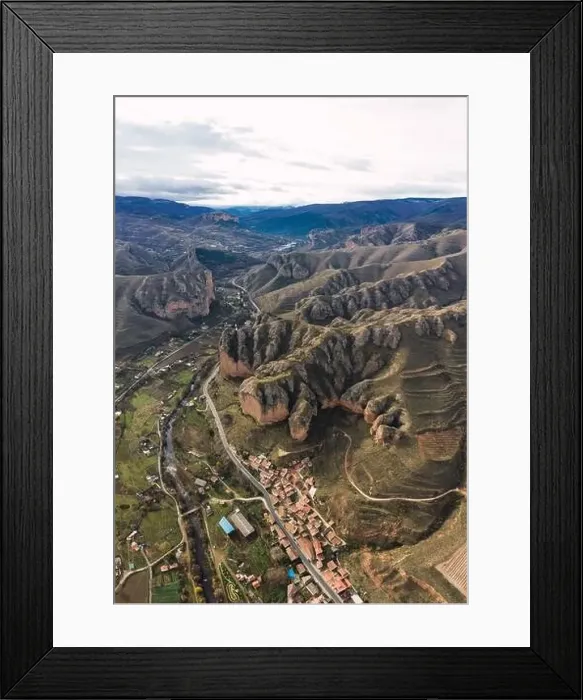 Framed Print : Aerial view of scenic green mountain slopes and buildings with road in valley Framed Print : Aerial view of scenic green mountain slopes and buildings with road in valley