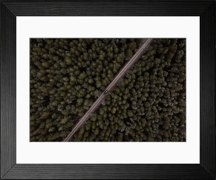 Framed Print : Drone view of lonely car driving along road in coniferous woods in winter in Scottish Highlands Framed Print : Drone view of lonely car driving along road in coniferous woods in winter in Scottish Highlands