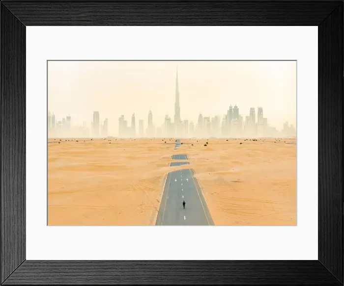 Framed Print : Aerial view of an unidentified person walking on a deserted road covered by sand dunes with the Dubai Skyline in Framed Print : Aerial view of an unidentified person walking on a deserted road covered by sand dunes with the Dubai Skyline in