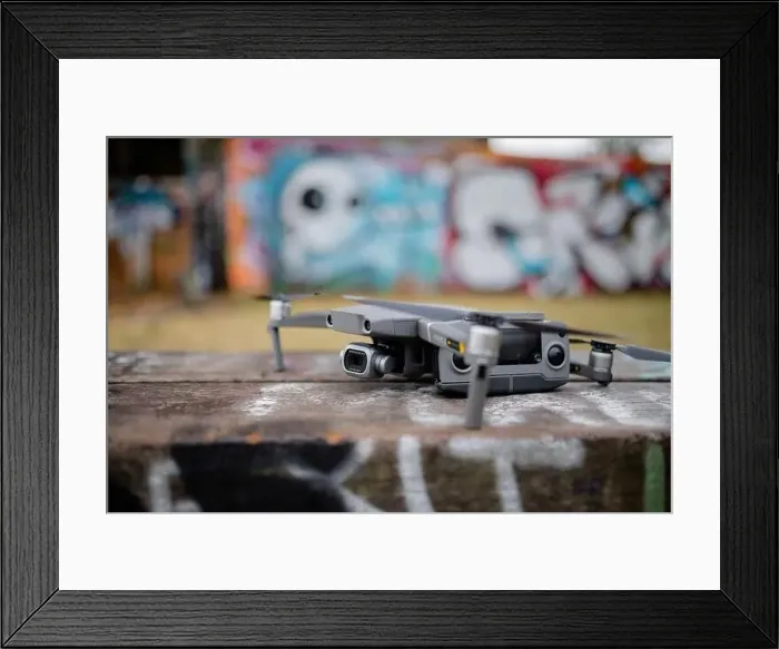 Framed Print : Landscape View of a Gray Drone with A Blurry Graffiti Wall in the Background Framed Print : Landscape View of a Gray Drone with A Blurry Graffiti Wall in the Background
