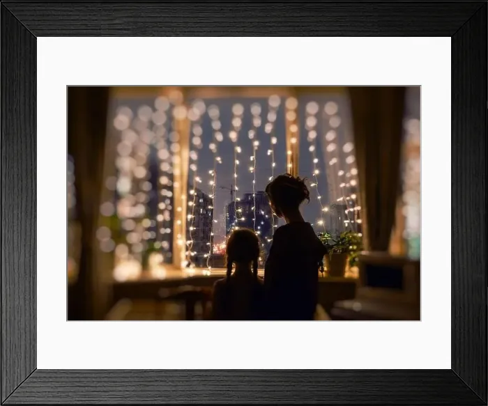 Framed Print : Mother and daughter together standing in the evening, watching the window lights, christmas mood Framed Print : Mother and daughter together standing in the evening, watching the window lights, christmas mood