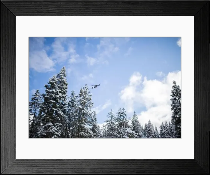 Framed Print : Drone flying over beautiful snowy forest under a blue sky Framed Print : Drone flying over beautiful snowy forest under a blue sky