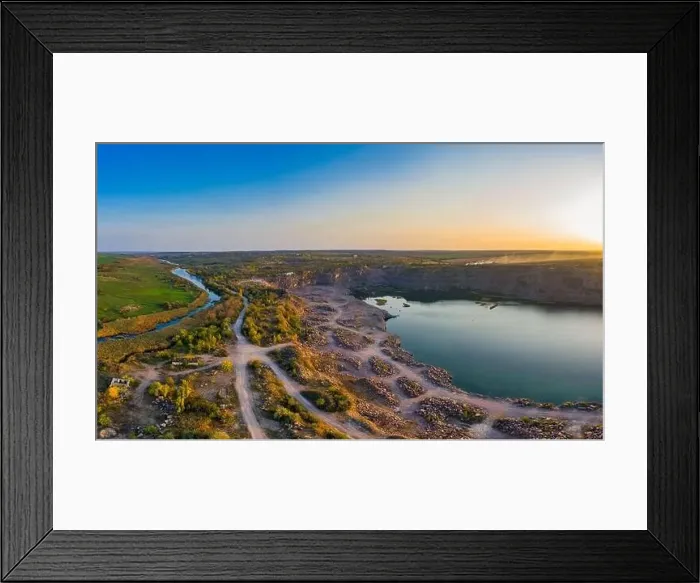 Framed Print : Old flooded stone quarry with large stones in the evening warm bright light covered with small dry plants in Framed Print : Old flooded stone quarry with large stones in the evening warm bright light covered with small dry plants in