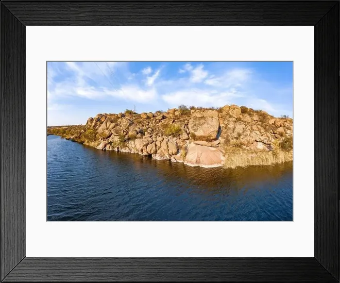 Framed Print : Among the large boulders, a smooth shining stream flows in the evening warm light in picturesque Ukraine