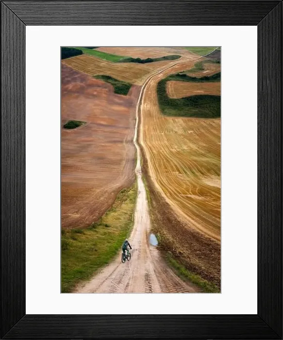 Framed Print : Cyclist on road amongst colorlful meadows in warp perspective, Mazury Poland Framed Print : Cyclist on road amongst colorlful meadows in warp perspective, Mazury Poland