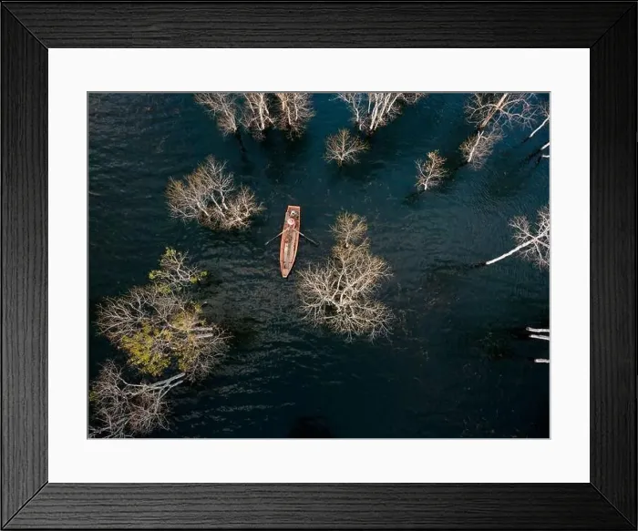 Framed Print : A boat travels on a deserted lake among the dry trees in the morning on a winter day Framed Print : A boat travels on a deserted lake among the dry trees in the morning on a winter day