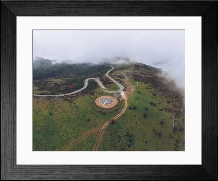 Framed Print : Spectacular drone view of curved serpent road near round concrete helipad on grassy rural valley on summer day running
