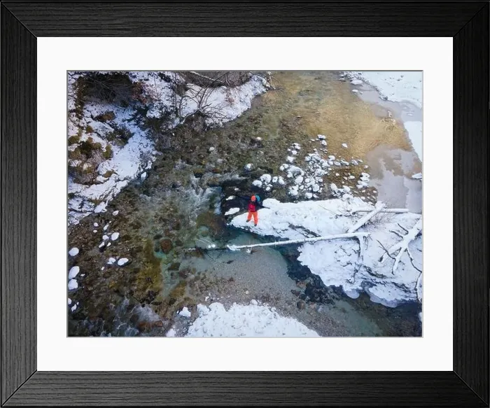 Framed Print : Aerial drone shot of hiker with backpack, orange cap and orange pants next to cold mountain stream in canyon Framed Print : Aerial drone shot of hiker with backpack, orange cap and orange pants next to cold mountain stream in canyon