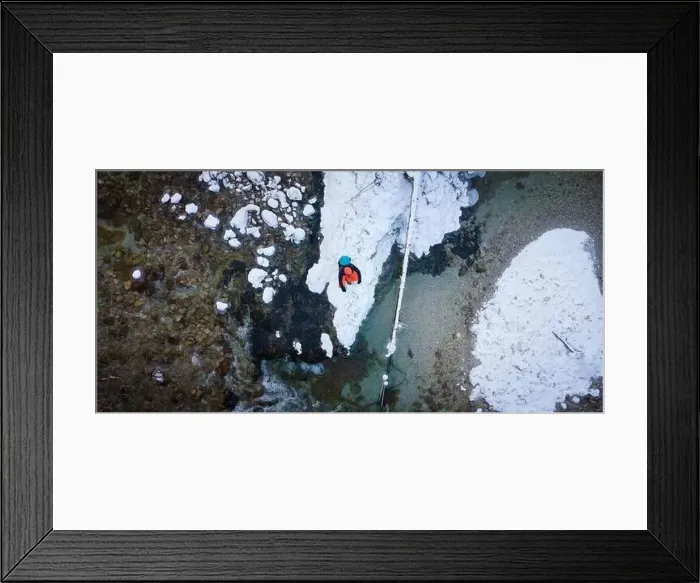 Framed Print : Aerial drone shot of hiker with backpack, orange cap and orange pants next to cold mountain stream in canyon Framed Print : Aerial drone shot of hiker with backpack, orange cap and orange pants next to cold mountain stream in canyon