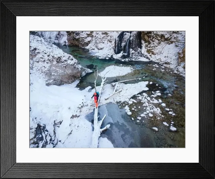 Framed Print : Aerial drone shot of hiker with backpack, orange cap and orange pants next to cold mountain stream in canyon Framed Print : Aerial drone shot of hiker with backpack, orange cap and orange pants next to cold mountain stream in canyon