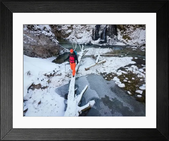 Framed Print : Aerial drone shot of hiker with backpack, orange cap and orange pants next to cold mountain stream in canyon Framed Print : Aerial drone shot of hiker with backpack, orange cap and orange pants next to cold mountain stream in canyon