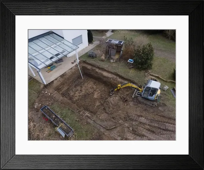 Framed Print : aerial drone shot of small, yellow excavator stands in a large garden and digs a hole for a pool in austria Framed Print : aerial drone shot of small, yellow excavator stands in a large garden and digs a hole for a pool in austria
