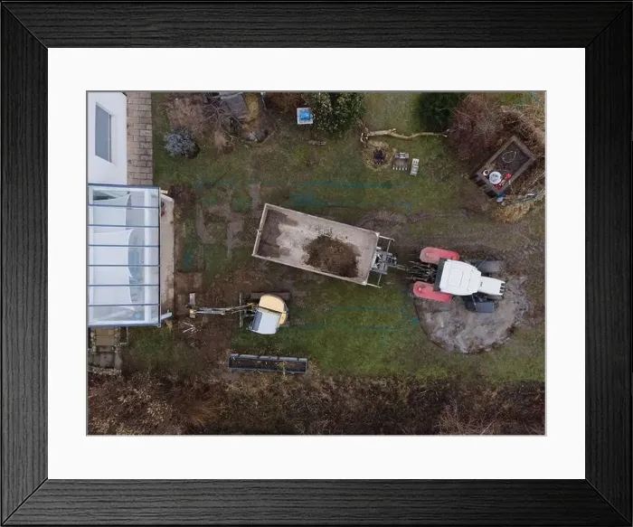 Framed Print : aerial drone shot of small, yellow excavator stands in a large garden and digs a hole for a pool in austria Framed Print : aerial drone shot of small, yellow excavator stands in a large garden and digs a hole for a pool in austria
